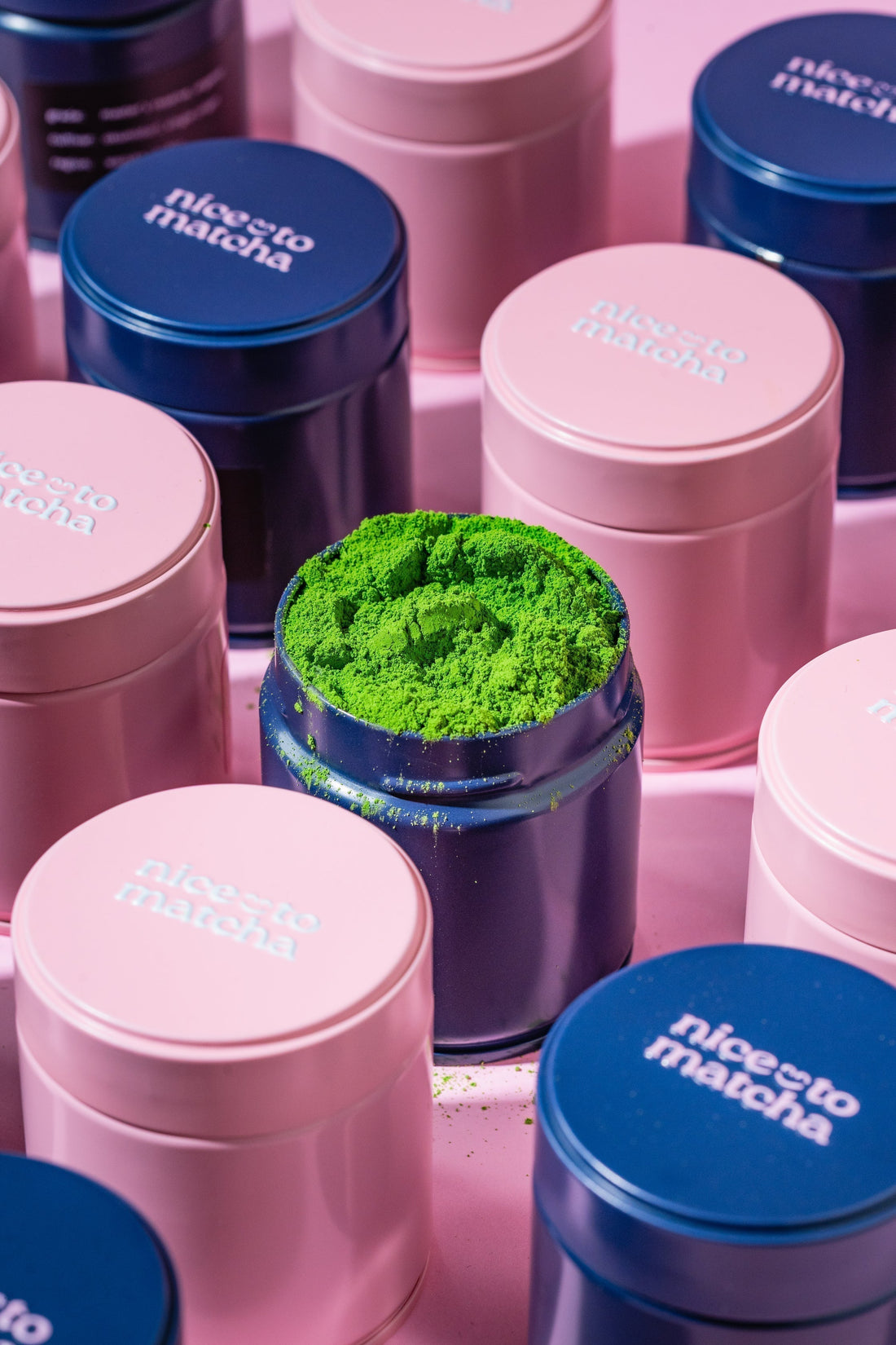Nice To Matcha tins and matcha preparation tools on pink background